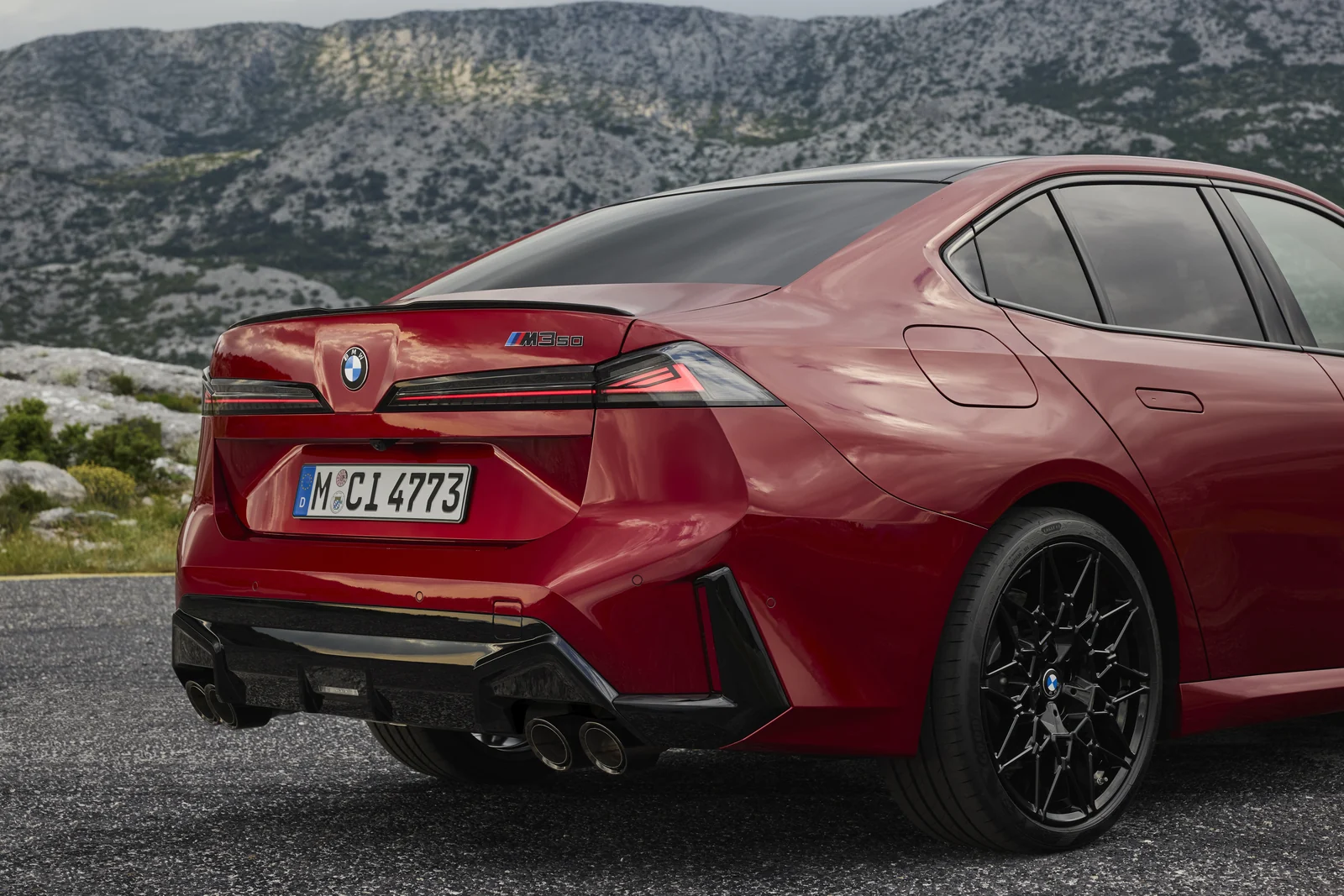 Röd BMW M350 xDrive snett bakifrån med fyra avgasrör och svarta fälgar.